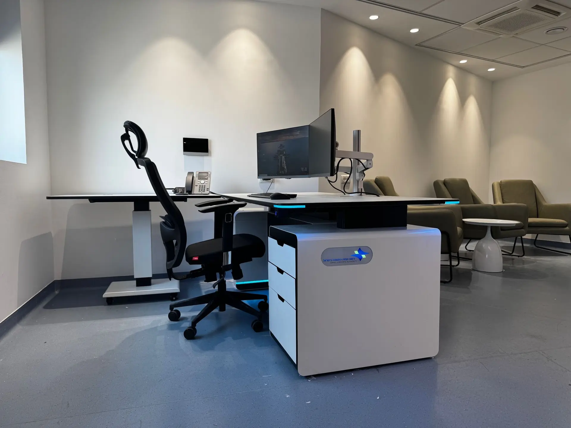Photograph of the completed workspace with a console, screens, and a seating area