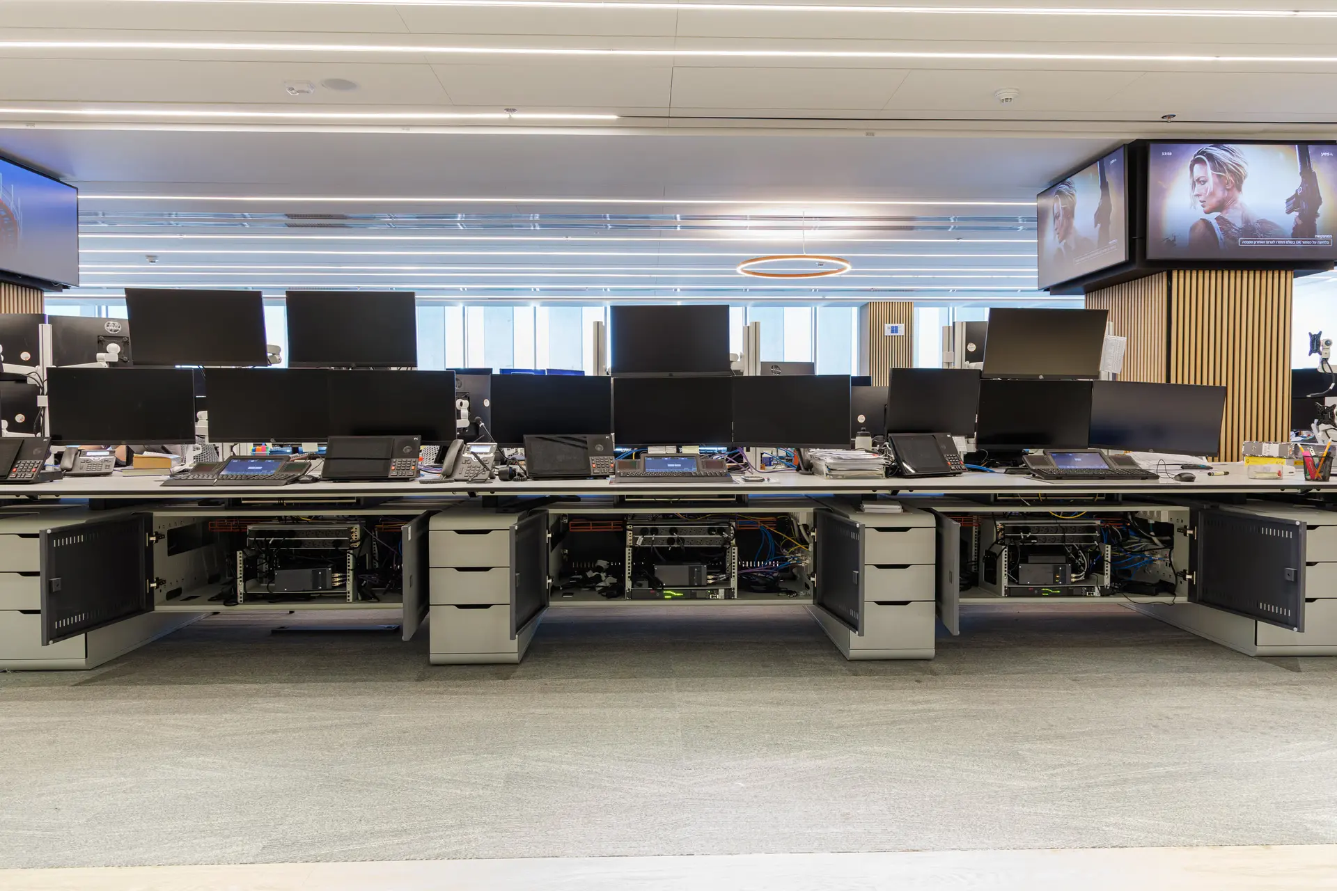 A row of trading-room workstations with the lower infrastructure cabinets open